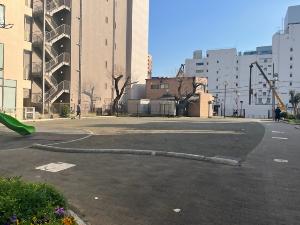 ビルやマンションの立ち並ぶ市街地の一角にある中町公園の多目的広場の写真