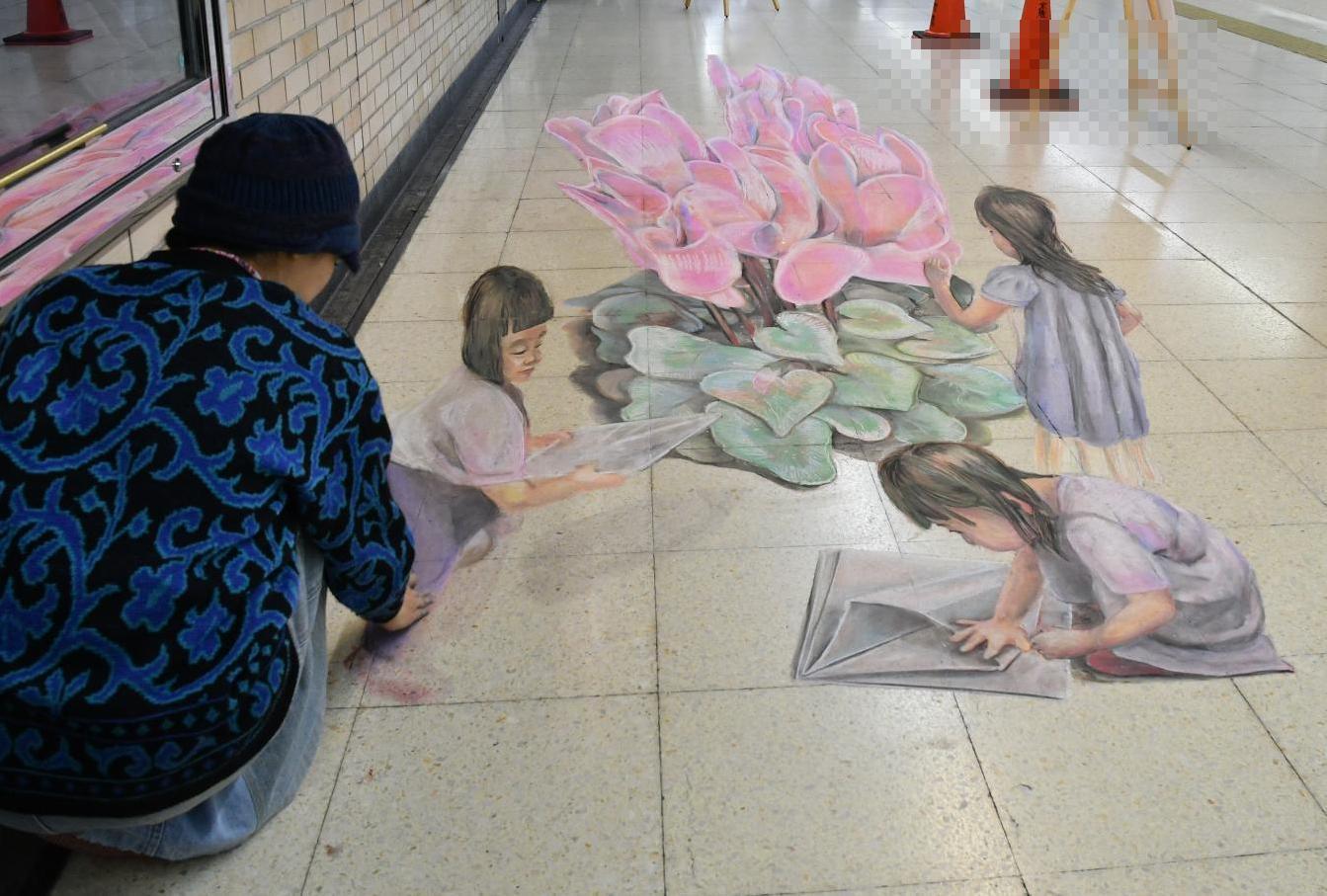 地下道の床に見事なトリックアートが描かれていく写真