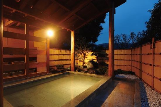 石でできた四角形のお風呂の周りに庭園が造られた飯山温泉郷・七沢温泉郷の露天風呂の写真