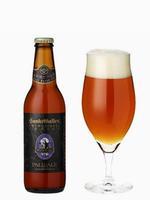 ペールエールのビール瓶とチューリップ型のグラスに注がれ赤褐色をしたビールの写真