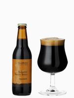 黒糖スイートスタウトのビール瓶とチューリップ型のグラスに注がれた黒色のビールの写真
