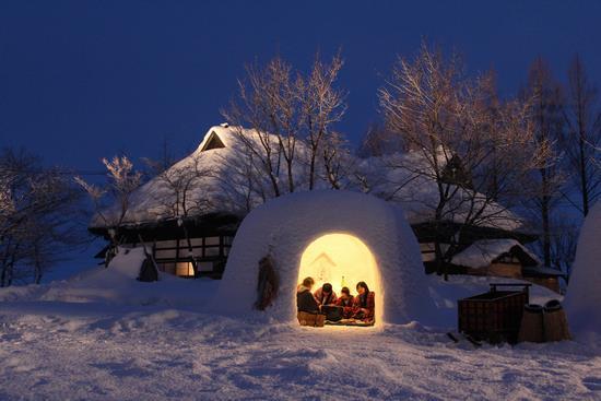 雪で作った「家」（雪洞）の中に子供たちが入っている「かまくら」の写真
