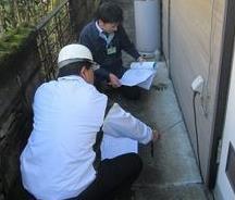 関係者2名が書類を見ながら、現地で建物の耐震診断を実施している写真