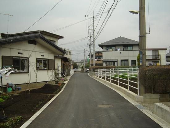 生活道路に白線が引かれ、道幅も広くなり、車両防護柵も設置された住宅街の写真