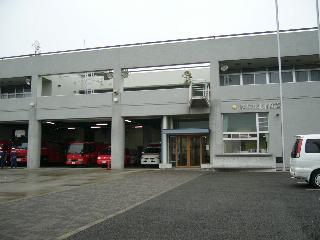 グレー色を基調とした2階建ての事務所に隣接する車庫に消防車両と救急車両が駐車されている北消防署本署の写真