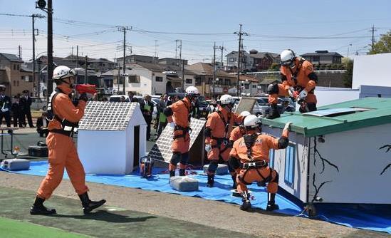 災害時に着用するオレンジ色の服にヘルメットを被った隊員が救助訓練をしている写真