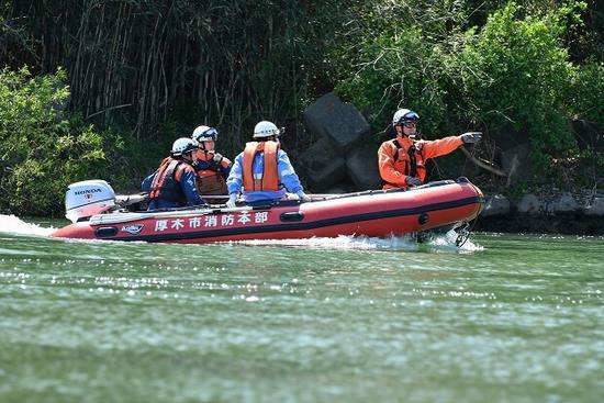 厚木市消防本部と書かれたボートに4名の消防隊員が乗り救助訓練を行っている写真