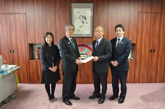 越智一久議長へ答申書を手渡す沼田幸一委員長と右端に黒のスーツ姿の女性と左端に紺のスーツ姿の男性が並んでいる写真