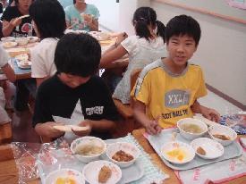 ランチルームで美味しそうに給食を食べる子供たちの写真