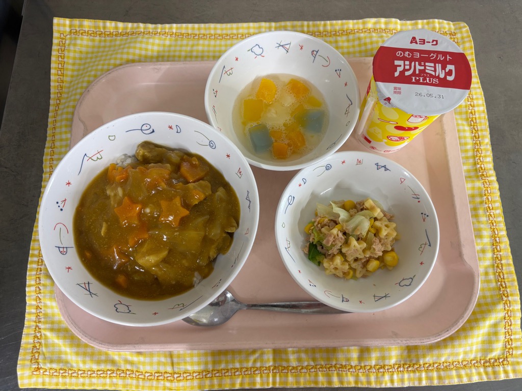 トレーの上に丼に盛られたベイスターズ青星寮カレー、飲むヨーグルト、お皿に盛られたステラサラダ、ゼリー入りフルーツミックス、スプーンが並べられている写真