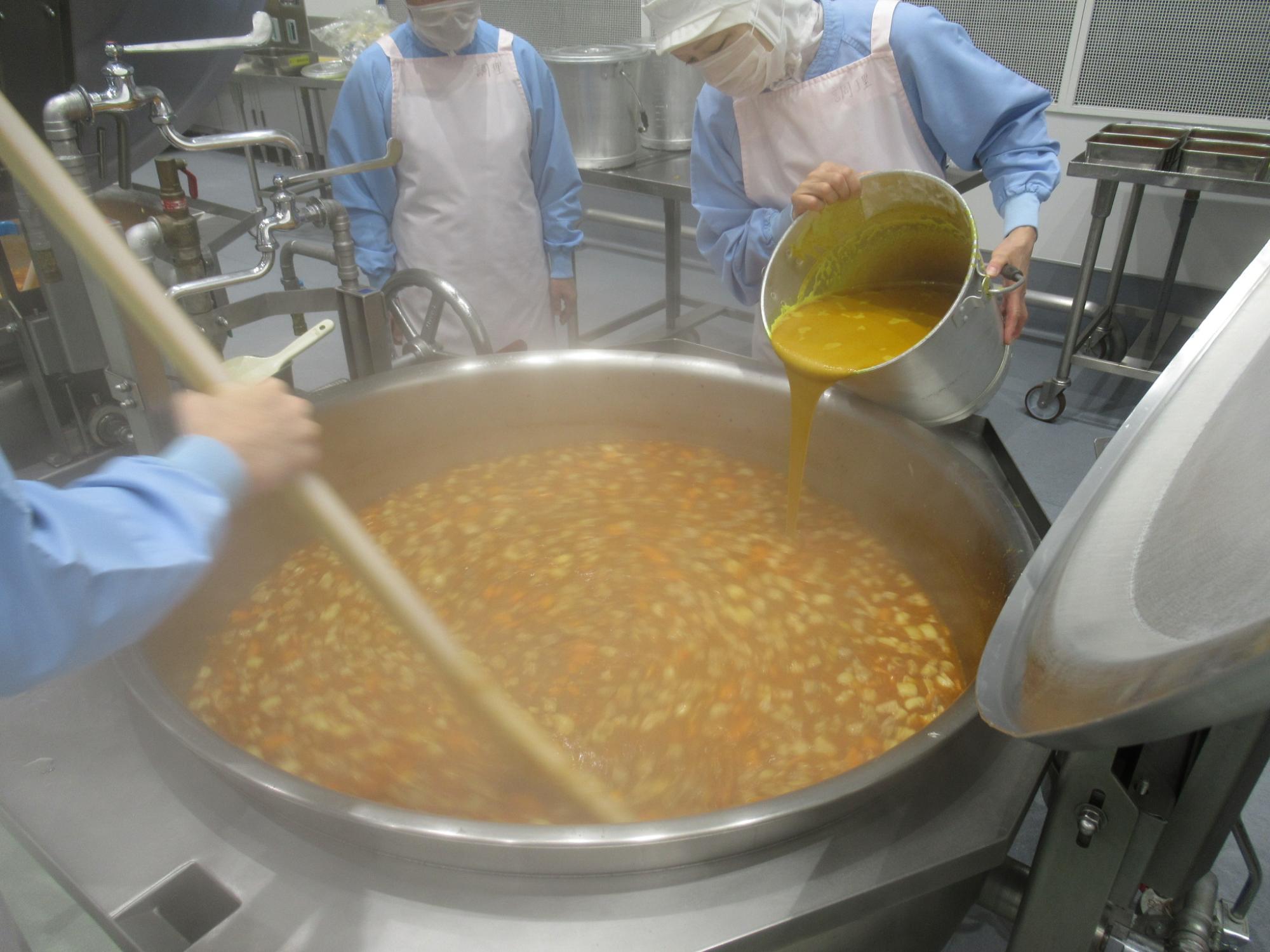 釜でカレーを調理している写真