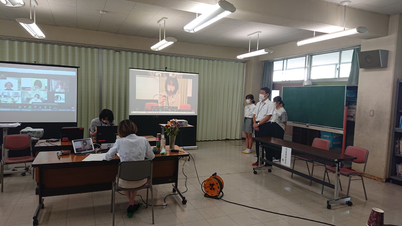 妻田小学校の教室にて先生と児童が集まり取組内容を報告している様子