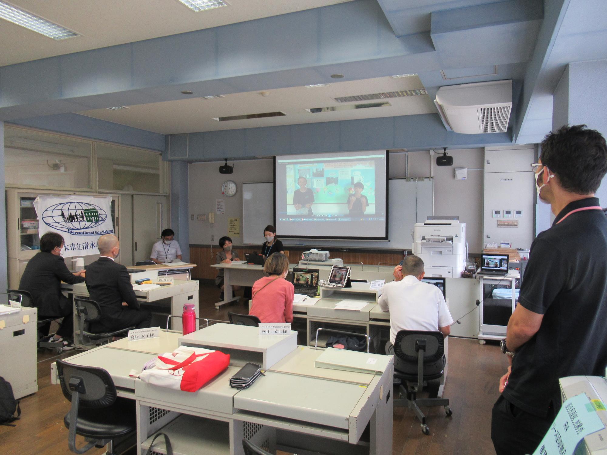 パソコン教室にてオンラインにて審査員2人に取組内容を発表している様子