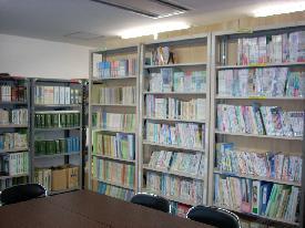 壁際の本棚に教育図書や資料がたくさん並んでおり、本棚の前にテーブルと椅子がある教育研究所の写真