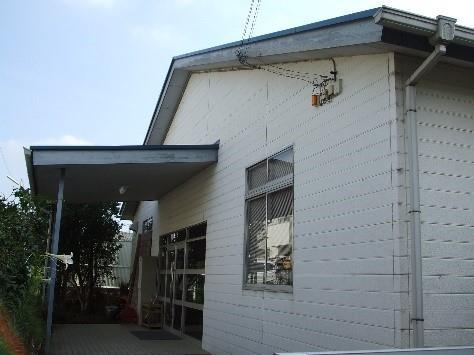 壁がオフホワイト色の建物で、入口の前に雨除けがある相談指導教室の建物の写真