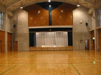 前方にステージがある天井の高い体育室内の写真