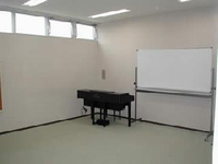 部屋の角にピアノとホワイトボードが置いてある音楽室の写真