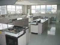 ガスコンロある調理台が間隔を空けて何台か設置されている調理室の写真