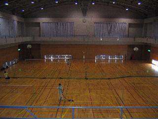 中央がグリーンのネットで仕切られている体育館の内部の写真