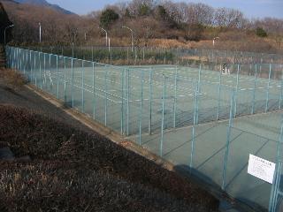 広々としたテニスコートをフェンスの外側から撮影した写真