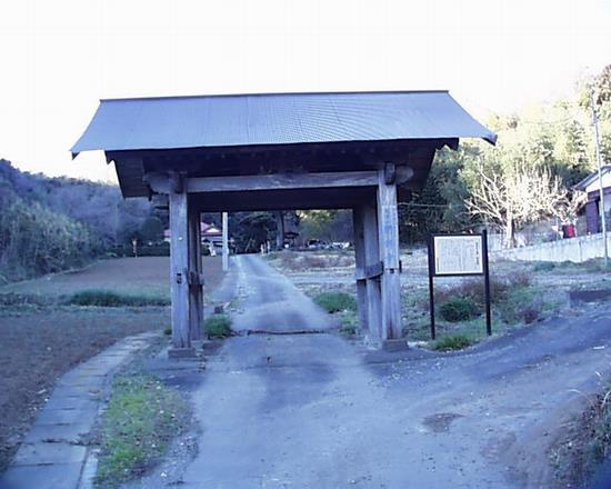 木製の柱の山門が正面にあり、門の奥に道が続いている写真