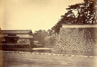 右側に上に向かって反っている石垣があり、水路を隔てて左側に大きな門構えの桜田門の白黒写真