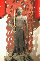 赤い炎を背にして、表情も険しく、右手で剣を握っている不動明王立像の写真