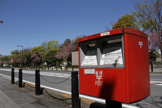 歩道の脇に赤い郵便ポストが設置されている写真