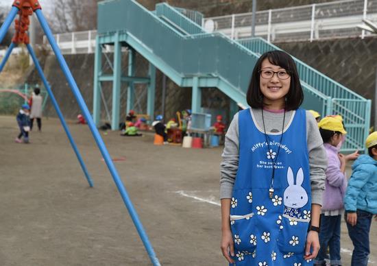 ウサギのキャラクターの青いエプロンをつけた女性保育士の写真