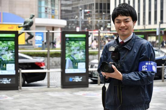 広報の腕章をつけてカメラを持っている男性職員の写真