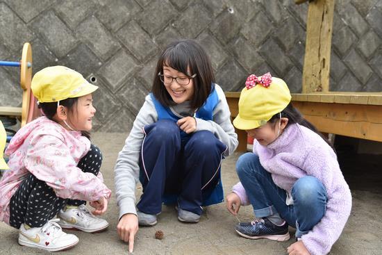 保育士の女性、2人の園児が笑顔で楽しそうに話をしている写真