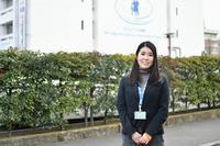 手を前に組んで笑顔で立っている障がい福祉課女性事務職員の写真