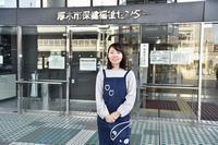 厚木保健福祉センターの前でエプロンをつけた女性が両手を前に揃えて立っている写真