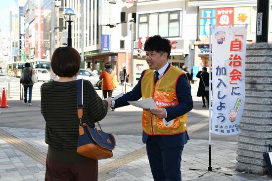街頭に立ち通りかかる市民にチラシを配っている男性職員の写真