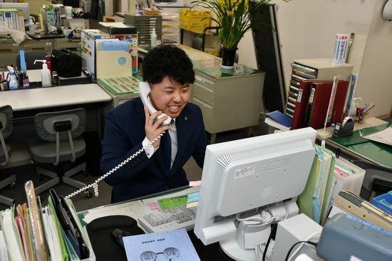 パソコンを見ながら電話応対をしている男性職員の写真