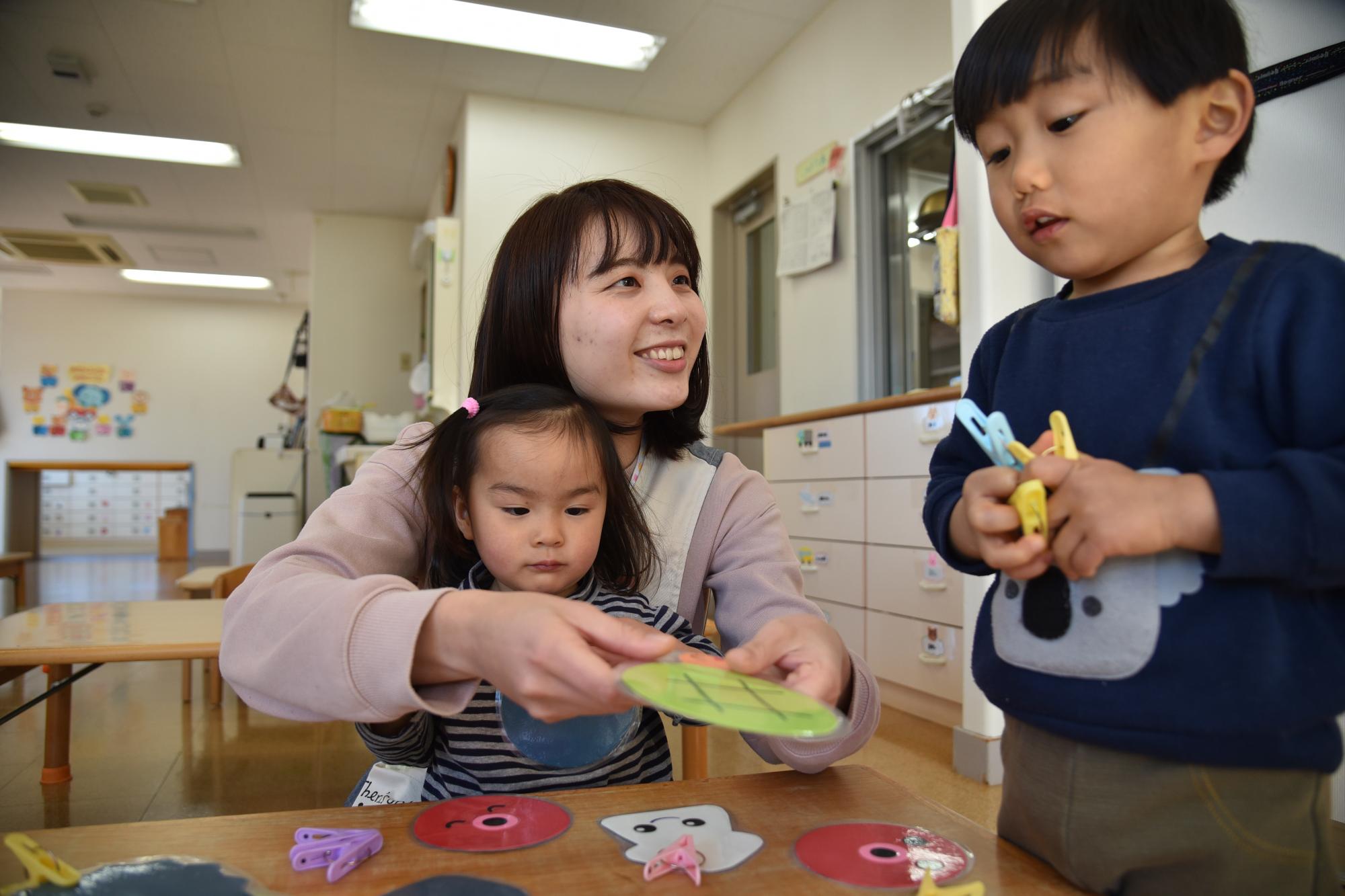 子どもたちと一緒に遊んでいる女性保育士の写真