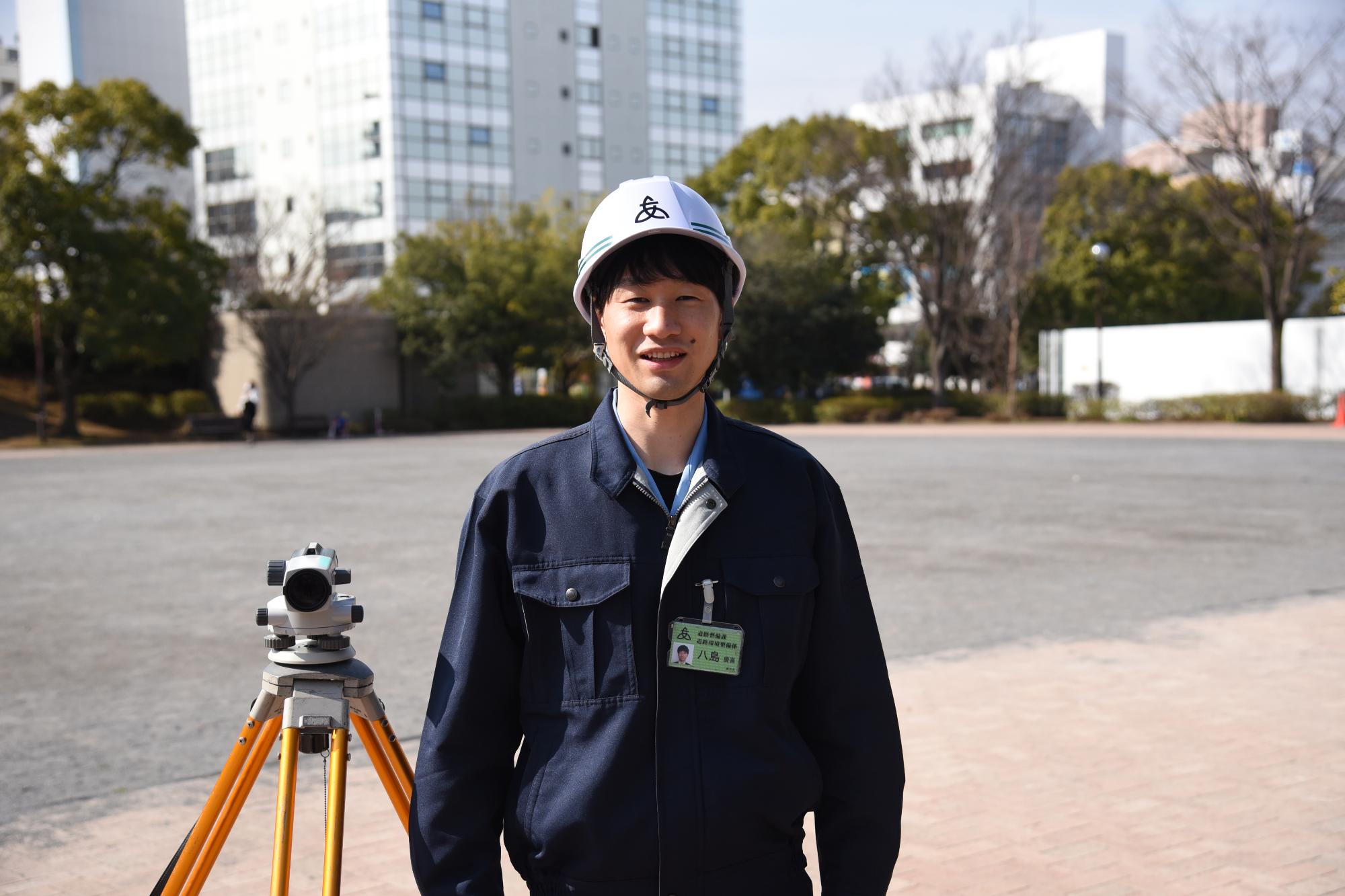 公園で作業着を着て笑顔で立っている土木職の男性職員の写真