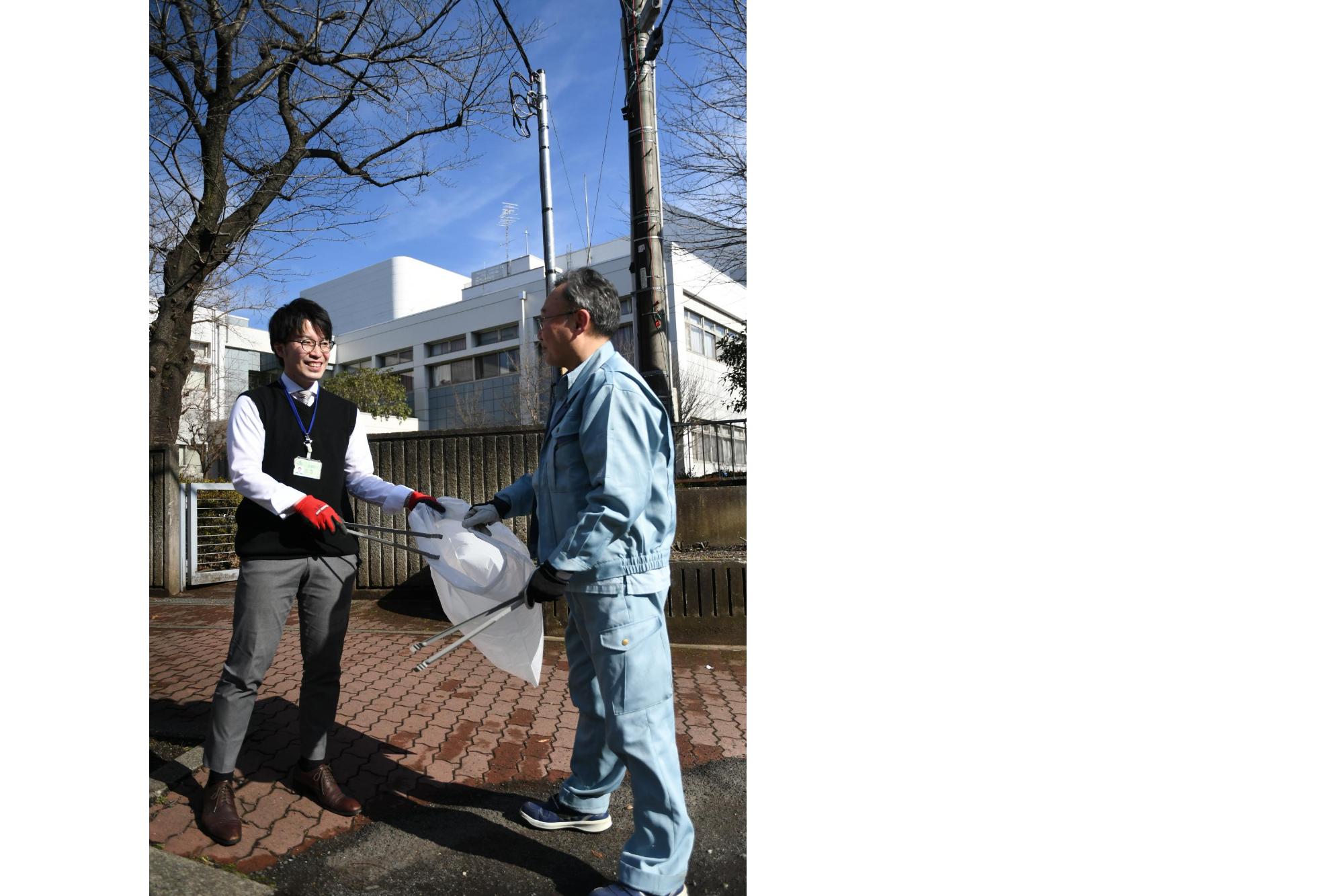 先輩職員と一緒にごみの回収をしている男性職員の写真