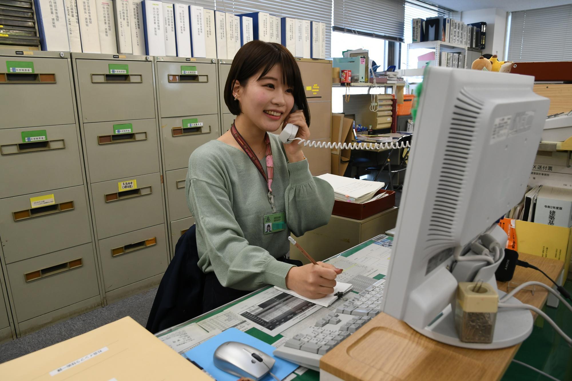 パソコンの画面を見ながら電話応対をしている建築職の女性職員の写真