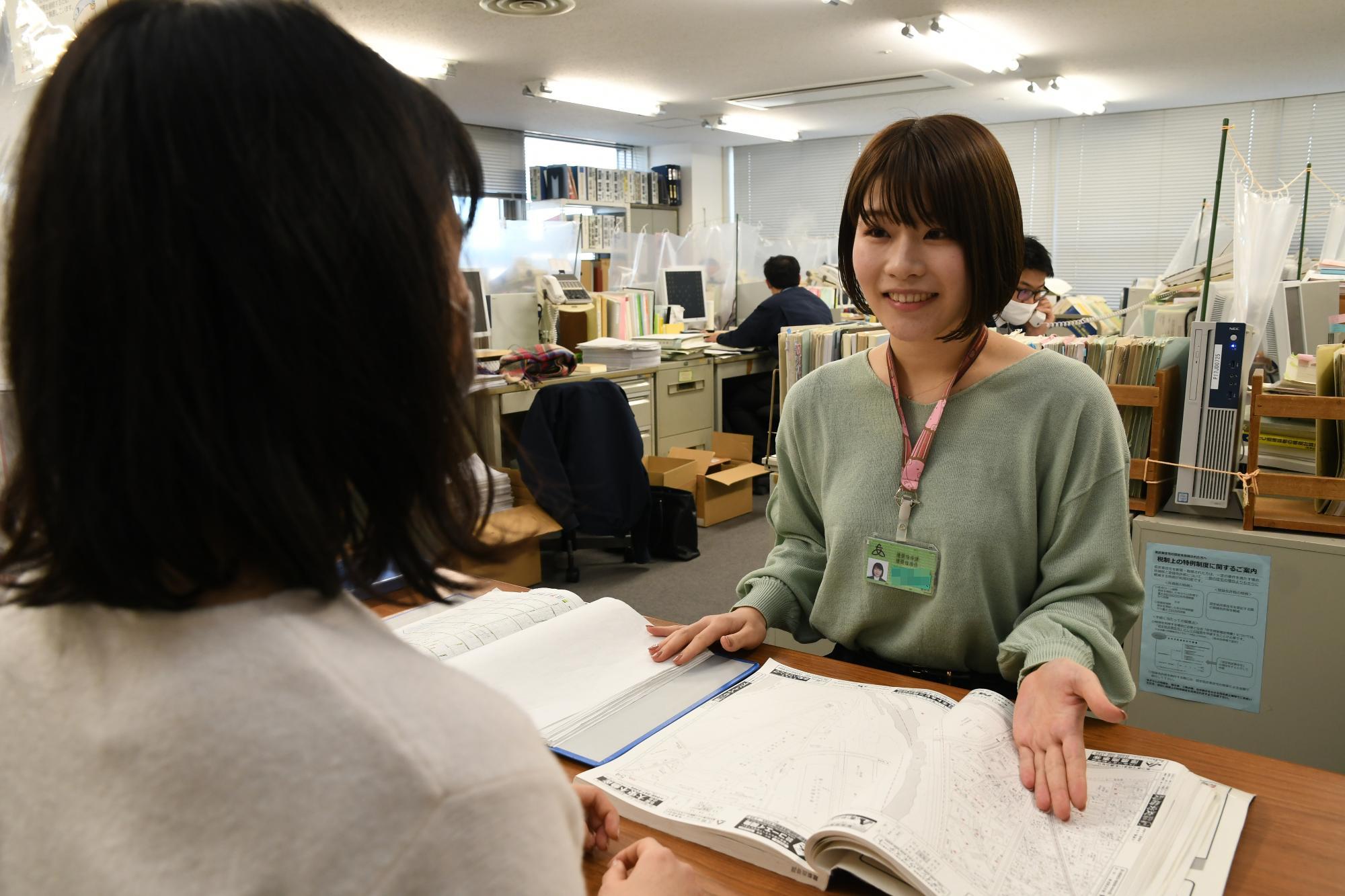 設計図を見せながら来庁者の対応をしている建築職の女性職員の写真