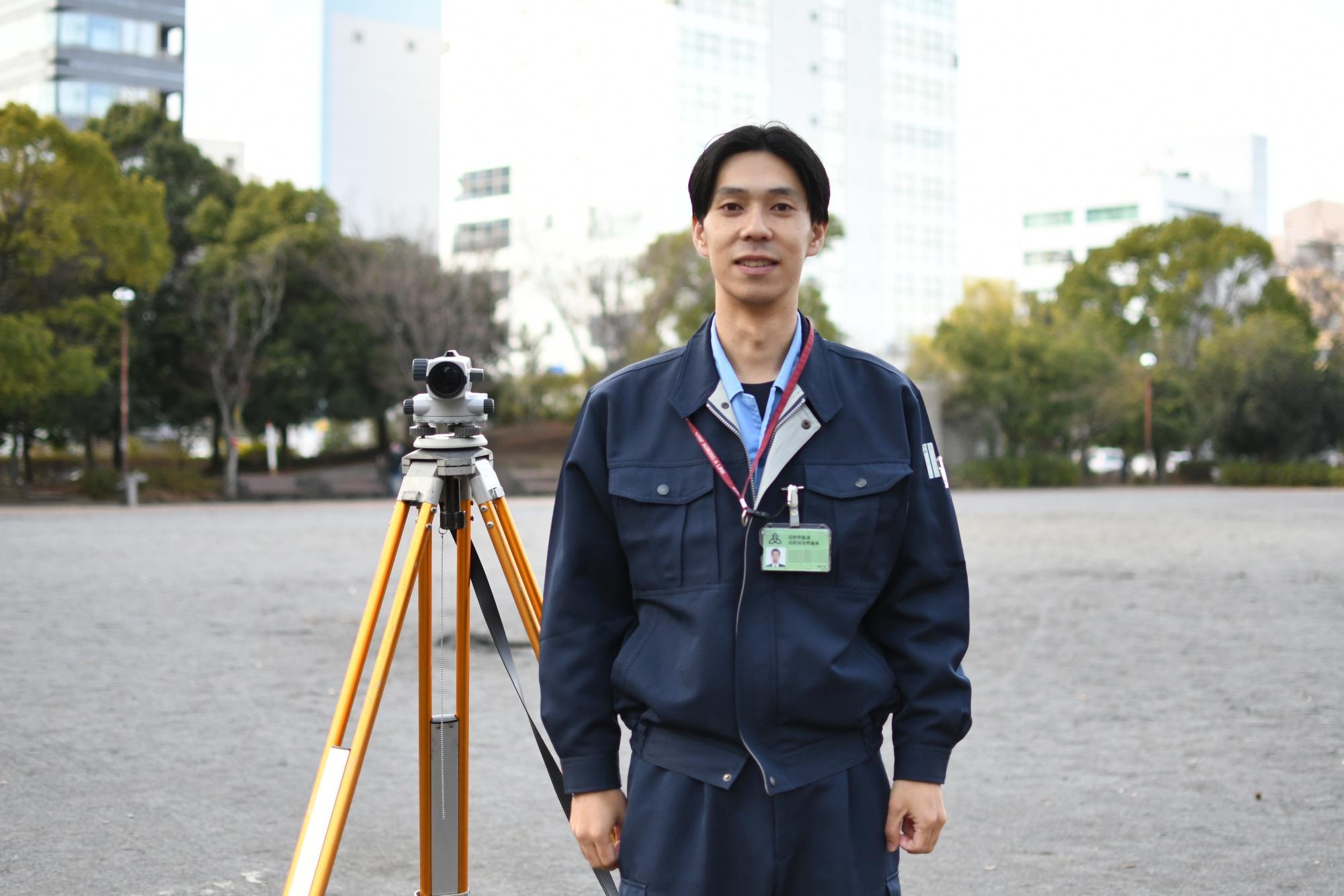 公園で作業着を着て笑顔で立っている土木職の男性職員の写真