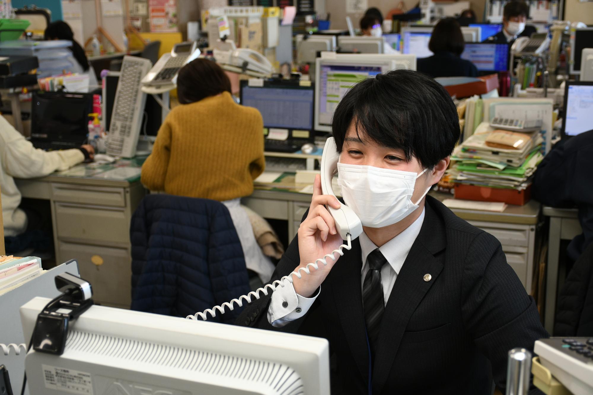 他の部署からの電話連絡に対応している男性職員の写真