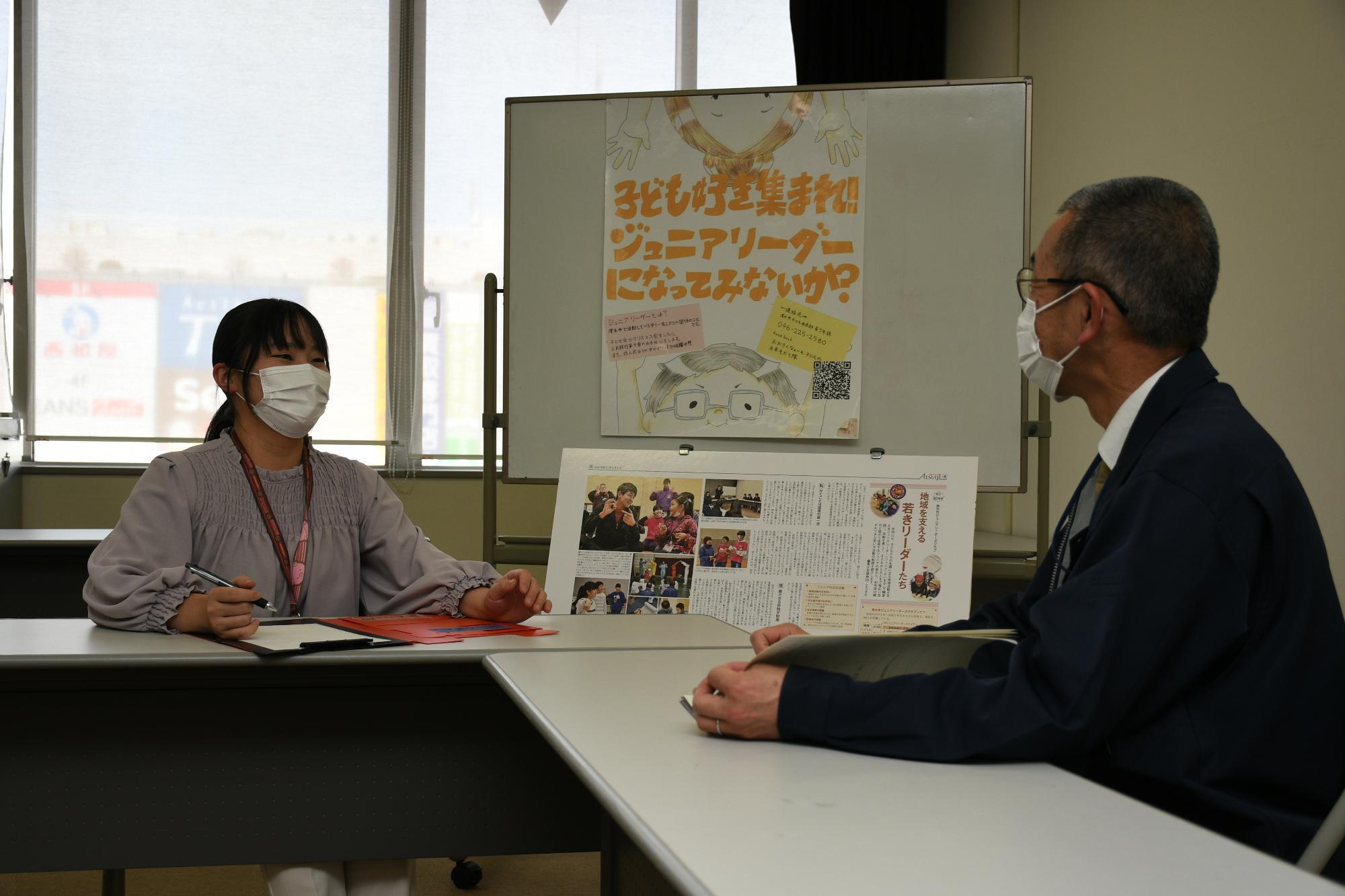 会議室で上司と会話をしている女性職員の写真