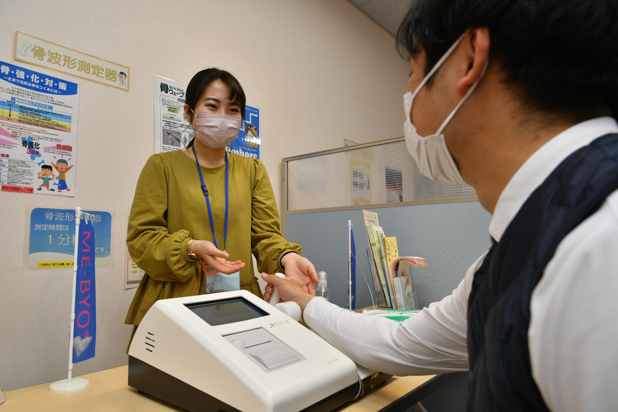 来館者の骨波形測定の対応をしている女性保健師の写真