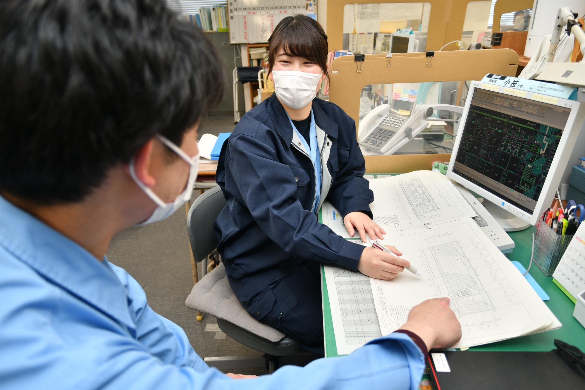 先輩職員に仕事の相談をしている建築職の女性職員の写真